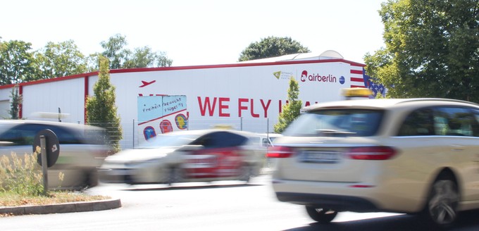 Wenige Hundert Meter weiter fahren Taxis an einem Zeugnis aus unbesorgteren Zeiten vorbei. In Anlehnung auf Barack Obamas legendären Wahlspruch, zierte ein „Yes we fly USA“ die ehemalige Gerätehalle und bewarb Flüge in die Vereinigten Staaten.