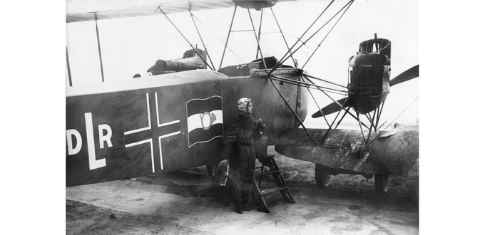 Die Abkürzung DLR für Deutsche Luftreederei, daneben ein Balkenkreuz aus Kriegszeiten und schließlich die Reichspostflagge.