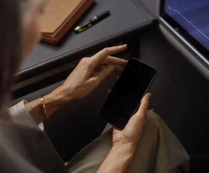 Lufthansa-Reisende hält ein Smartphone: Der Konzern wird alle 850 Flugzeuge mit Starlink ausstatten.