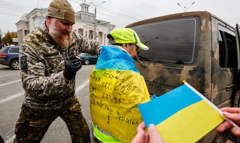 Ein Soldat unterschreibt die ukrainische Flagge, die ein Junge in Kherson trägt. Die ukrainische Armee wurde beim Einmarsch in Kherson freudig begrüßt.