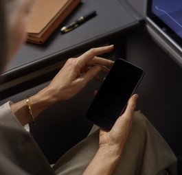 Lufthansa-Reisende hält ein Smartphone: Der Konzern wird alle 850 Flugzeuge mit Starlink ausstatten.