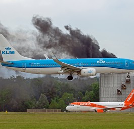 Eine Maschine von KLM fliegt am brennenden Gebäude ...