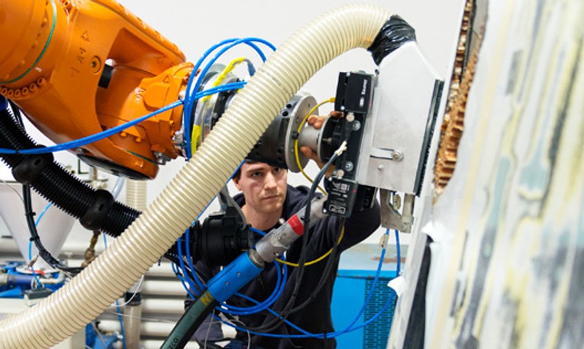 Neues System zur Entfernung von Lack: Ein Mensch nutzt den Roboter als intelligentes Werkzeug.