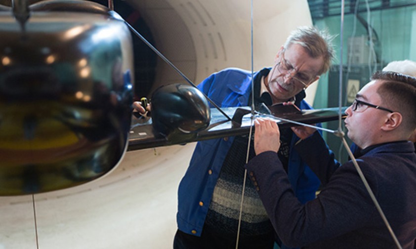 Forscher des Tsagi schauen sich ein Modell des neuen Fliegers an. Sie ...