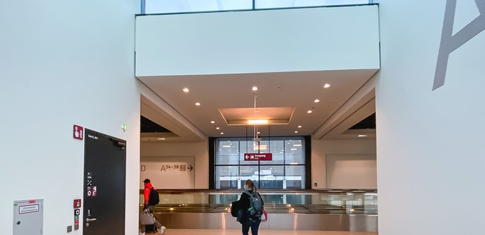 Der erste Anblick des neuen Terminals nach dem Aussteigen. In diesem Korridor bilden sich zukünftig die Warteschlangen zum Einsteigen. Das Laufband verbindet quer dazu die verschiedenen Gates miteinander.